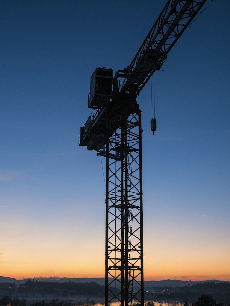 Baukran vor dem Abendhimmel über einer Baustelle