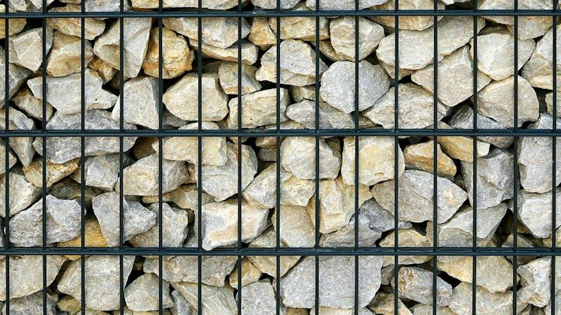 Gabionenwand aus hellem Naturstein in anthrazitfarbenem Drahtgitter